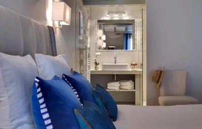a bedroom with a bed with blue pillows and a mirror at Hôtel Le Pré Saint Michel in Manosque