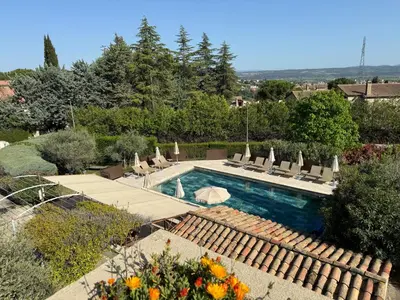 a swimming pool in a yard with lounge chairs at Hôtel Le Pré Saint Michel in Manosque