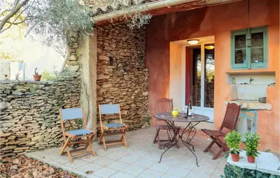 a patio with a table and chairs and a stone wall at Cozy Apartment In Villes Sur Auzon in Villes-sur-Auzon