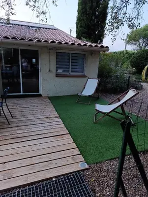 a wooden deck with two chairs on a lawn at Maison de campagne in Lançon-Provence
