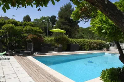 a swimming pool with chairs and an umbrella at L’ocabée in La Tour-dʼAigues