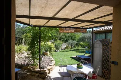 a patio with a table and chairs under a pergola at L’ocabée in La Tour-dʼAigues