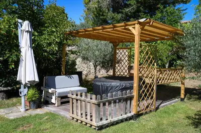 a wooden gazebo with a chair and an umbrella at L’ocabée in La Tour-dʼAigues