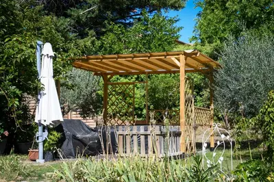a wooden gazebo with a white umbrella at L’ocabée in La Tour-dʼAigues