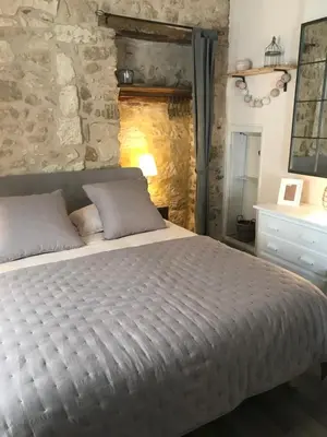 a bedroom with a bed and a stone wall at Au cœur de Céreste in Céreste