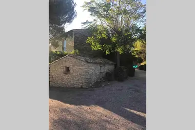 a stone building with a tree in the background at Le Bastidon de L Olivier in Gordes