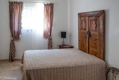 a bedroom with a bed and a wooden door and a window at Mas du Kairos - Gite Romarin in Venasque