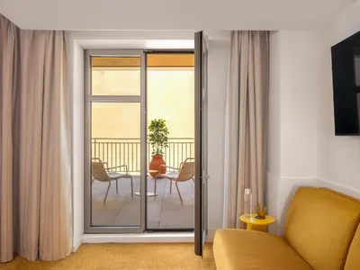 a living room with a sliding glass door to a balcony at Hôtel Saint Christophe Aix en Provence Centre Ville in Aix-en-Provence