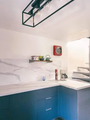 a kitchen with blue cabinets and a clock on the wall at LE BELVEDERE in LʼIsle-sur-la-Sorgue