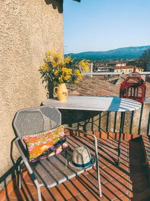 a table and chair with a hat on a balcony at LE BELVEDERE in LʼIsle-sur-la-Sorgue
