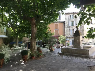 a park with a fountain and a tree and chairs at Chez Marius Gordes Vue panoramique sur luberon in Gordes