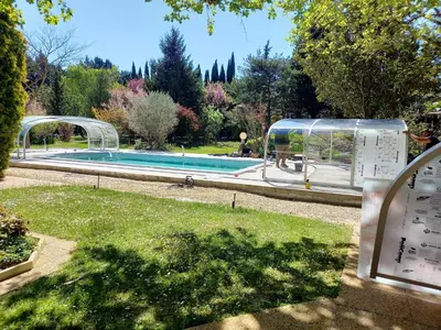 a swimming pool in a garden next to a park at Maison Le Thor avec piscine part. in Le Thor