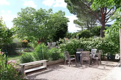 a table and chairs in a garden with a bench at IA ORANA in Gargas