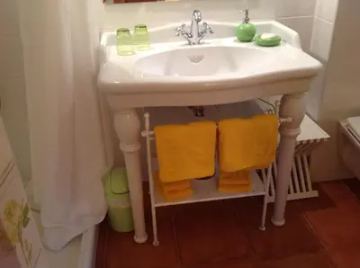 a bathroom sink with yellow towels under it at La Villa Rosalie in Ventabren