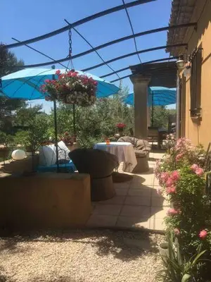 a patio with a table and a blue umbrella at Maison de famille au coeur du Luberon in Mérindol