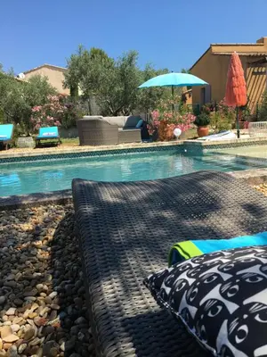 a bed next to a swimming pool with an umbrella at Maison de famille au coeur du Luberon in Mérindol