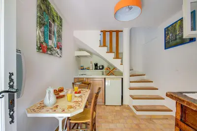 a kitchen and dining room with a table and a staircase at Les Chambres du Perussier in Cucuron