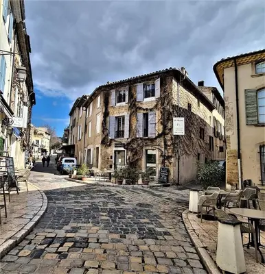 a cobblestone street in a town with a building at Maison La Plaine in Lourmarin