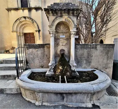 a water fountain in front of a building at Maison La Plaine in Lourmarin