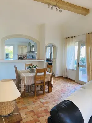 a living room with a table and a kitchen at Maison La Plaine in Lourmarin