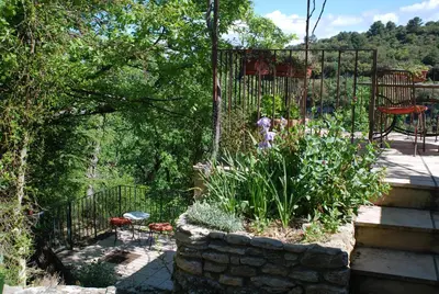 a garden with a stone planter and a fence at La maison jaune in La Roque-sur-Pernes