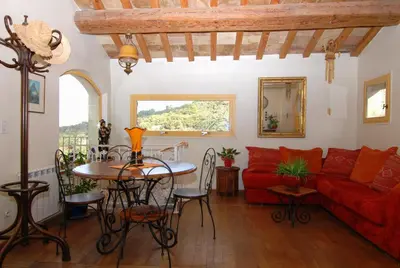 a living room with a red couch and a table at La maison jaune in La Roque-sur-Pernes