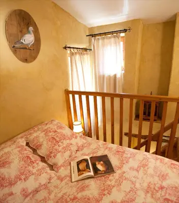 a bedroom with a bed with a book on it at La Fontaine in Simiane-la-Rotonde