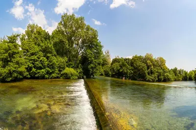 a river with trees on the side of it at Stone house in Isle-sur-la-Sorgue in LʼIsle-sur-la-Sorgue