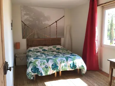 a bedroom with a bed with a bridge painting on the wall at Mas du Figuier Oppede Luberon in Oppède