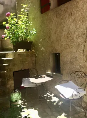 a patio with two chairs and a table and flowers at LA MAISON D’ALICE in Sault-de-Vaucluse