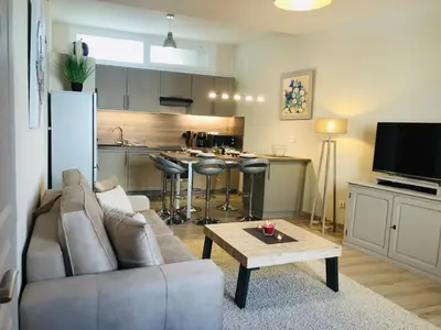 a living room with a couch and a table and a kitchen at Les volets rouges in Cavaillon