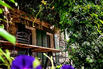 a bench sitting outside of a window with purple flowers at Mas La Pomarede in Robion en Luberon