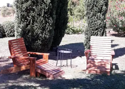 two wooden benches sitting in a yard with a chair at Mas La Pomarede in Robion en Luberon