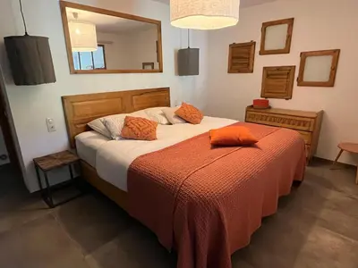 a bedroom with a bed with an orange blanket and a mirror at Domaine Hestia in Robion en Luberon