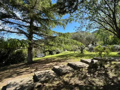 a park with trees and benches in the grass at Domaine Hestia in Robion en Luberon