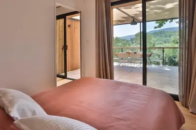 a bedroom with a bed and a view of a deck at Les Cabanes de la Fontaine in Lacoste