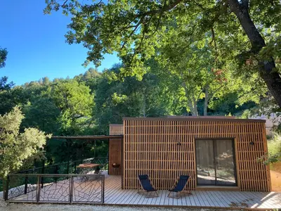 a wooden house with two blue chairs on a deck at Les Cabanes de la Fontaine in Lacoste