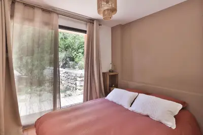 a bedroom with a bed and a large window at Les Cabanes de la Fontaine in Lacoste