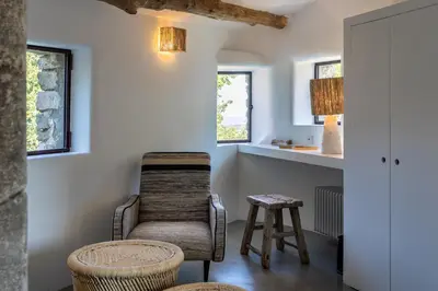 a room with a chair and a stool and windows at Le Domaine du Castellas in Sivergues