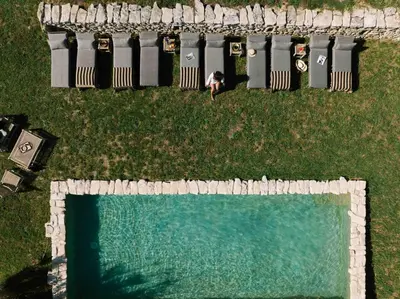 a woman is standing next to a swimming pool at Le Domaine du Castellas in Sivergues
