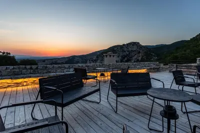 a deck with benches and tables and a sunset at Le Domaine du Castellas in Sivergues