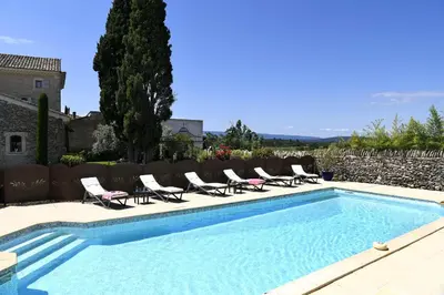 a swimming pool with lounge chairs next to a building at Bastide Des Demoiselles in Roussillon