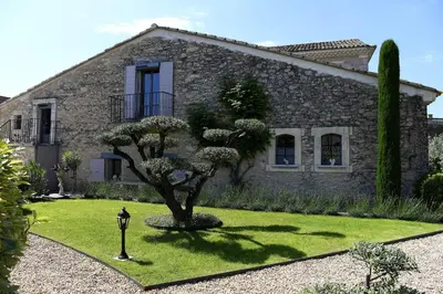 a stone house with a tree in front of it at Bastide Des Demoiselles in Roussillon