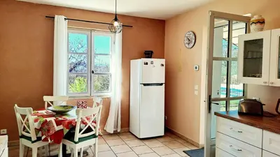 a kitchen with a table and a white refrigerator at La Bastide de l'Olivier in Flassan