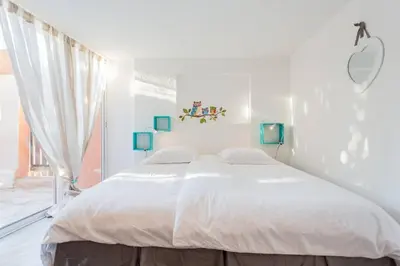 a white bedroom with a large bed and a window at La maison de Tao in Aix-en-Provence
