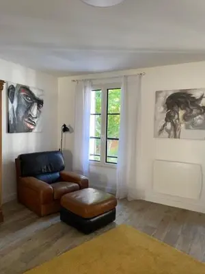 a living room with a chair and a stool at Maison de charme Isle sur la Sorgue in LʼIsle-sur-la-Sorgue