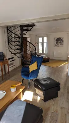 a living room with a blue chair and a spiral staircase at Maison de charme Isle sur la Sorgue in LʼIsle-sur-la-Sorgue