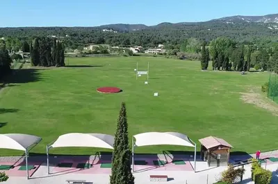 a view of a golf course with tents and a green field at Vue panoramique sur le château,montagne et grottes in Fontaine-de-Vaucluse