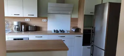 a kitchen with white cabinets and a stainless steel refrigerator at Loue haut de villa au calme piscine jardin arboré in Cornillon-Confoux