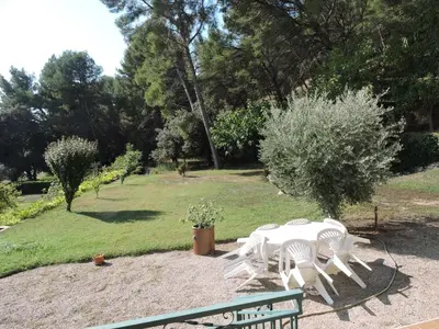 a white table and chairs in a garden at Loue haut de villa au calme piscine jardin arboré in Cornillon-Confoux